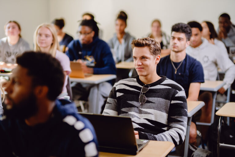 Goldey-Beacom student, Jason Ricker, looking mildly amused during a lection in a classroom of undergraduate students.
