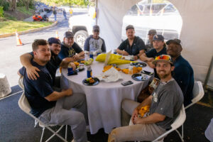 A table of people under a tent at an Alumni event on campus.