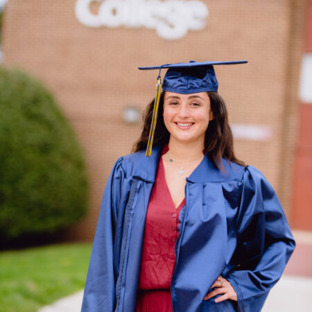 A portrait of Imane in commencement regalia on campus at Goldey-Beacom College