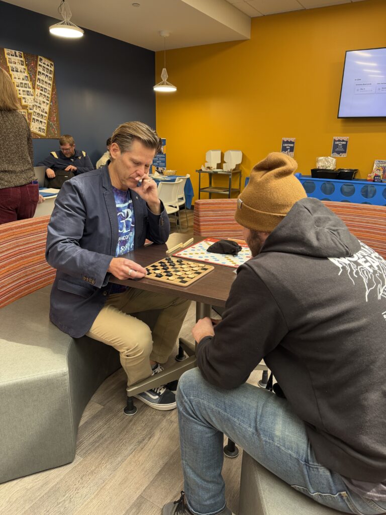 Joel playing checkers with a student.