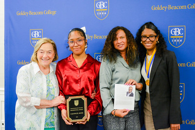 Family members of Calvin St. Juste stand together and smile while holding up a photo of Calvin and the presidential award he won at GBC's Distinguished Alumni Gallery Awards Dinner.