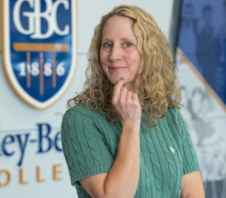 Professor Brandee El-Attar posing with her hand on her chin on a headshot