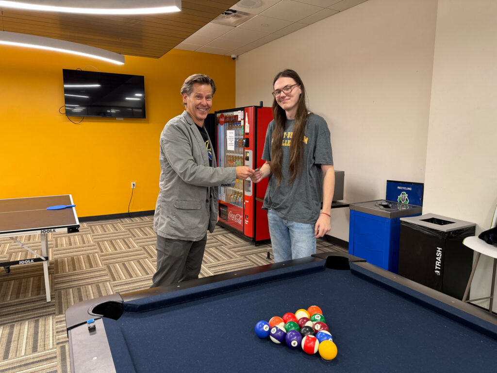 Chase Culligan, GBC student, receives $5 from provost, Joel Worden, for registering for classes and then beating Dr. Worden at a game of pool.