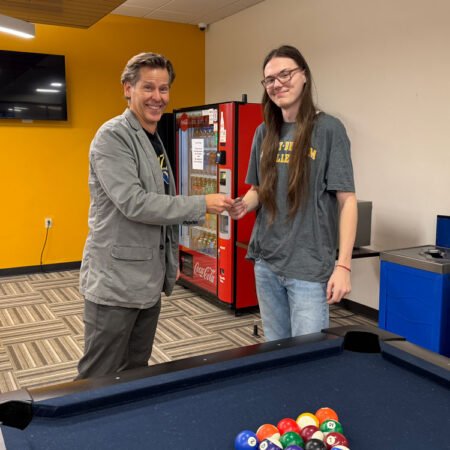 Chase Culligan, GBC student, receives $5 from provost, Joel Worden, for registering for classes and then beating Dr. Worden at a game of pool
