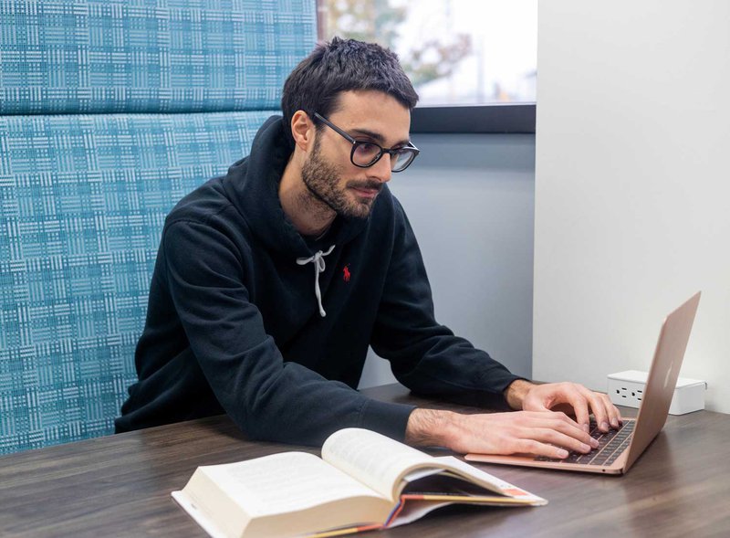 MBA in Business Analytics student on his laptop in the GBC library