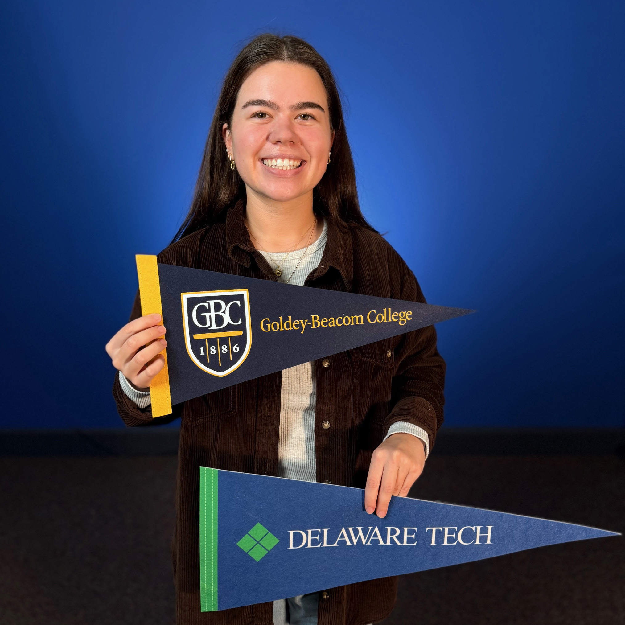 Gia Raffa, transfer student at GBC, holding flags from her first school, Delaware Tech, and current school, Goldey-Beacom