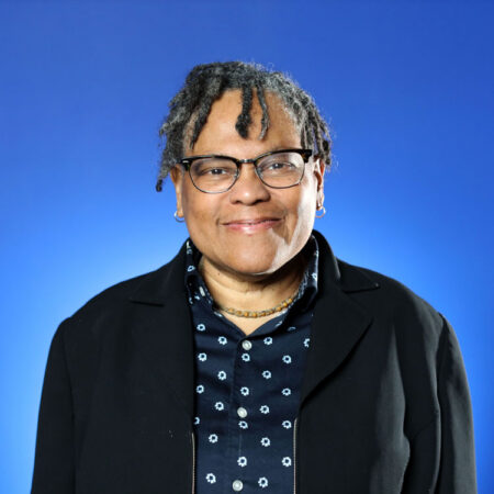 Melvina Brown standing in front of a blue background.