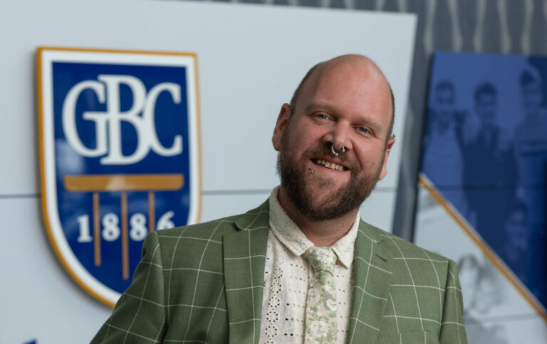 Randle Reed standing in front of a GBC shield with a smile.